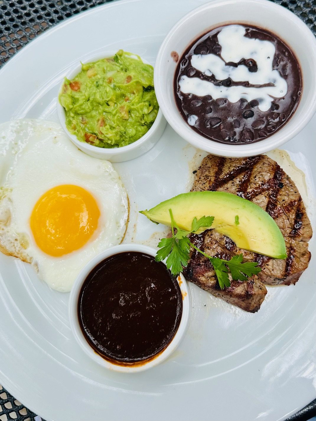 Brunch Lomo de Res — grilled beef tenderloin with a farm egg, guacamole, black beans, avocado and chile pasilla salsa