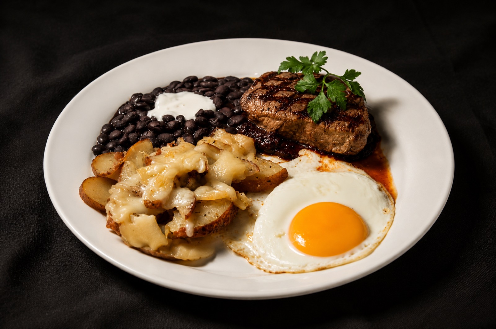 Steak & eggs — grilled beef tenderloin with chile pasilla salsa, a farm egg, cheesy potatoes and black beans with crema