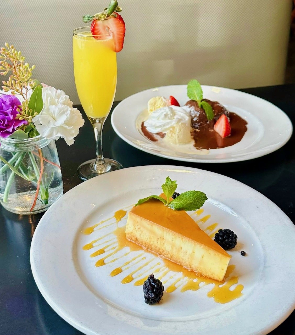 Signature flan and chocolate budín with vanilla ice cream and berries, alongside a mimosa