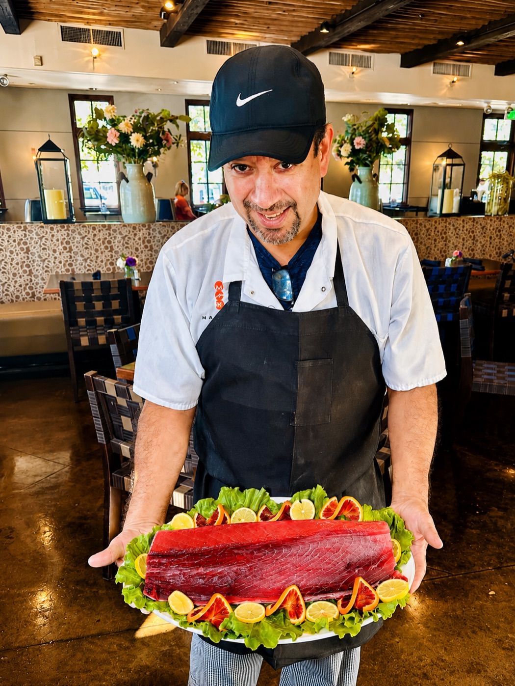 A Manuel's cook presenting a whole fresh tuna loin on a garnished platter