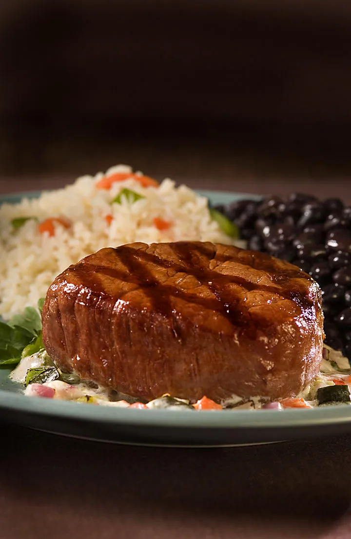 Grilled beef tenderloin with grill marks over Mexican rice, black beans and roasted-vegetable cream