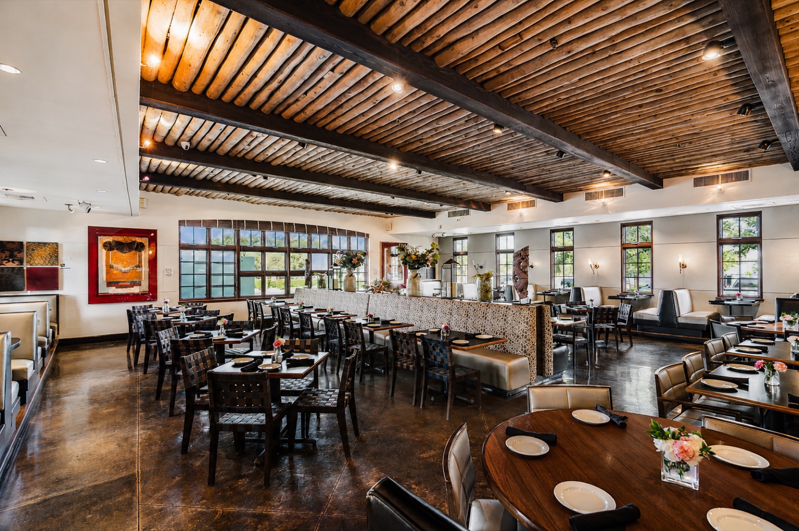 Manuel's dining room with a round wood table in the foreground, banquette divider and gallery windows, set for a private party