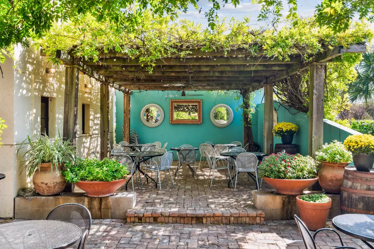 The pergola patio at Manuel's Great Hills — wisteria vines over the turquoise wall