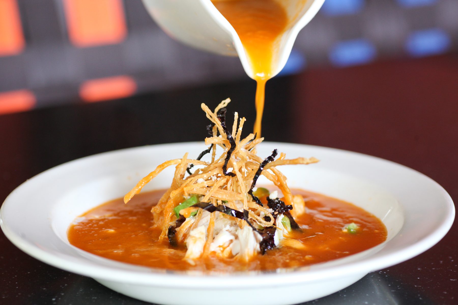 Sopa de tortilla poured tableside over avocado, crema and crisp tortilla strips